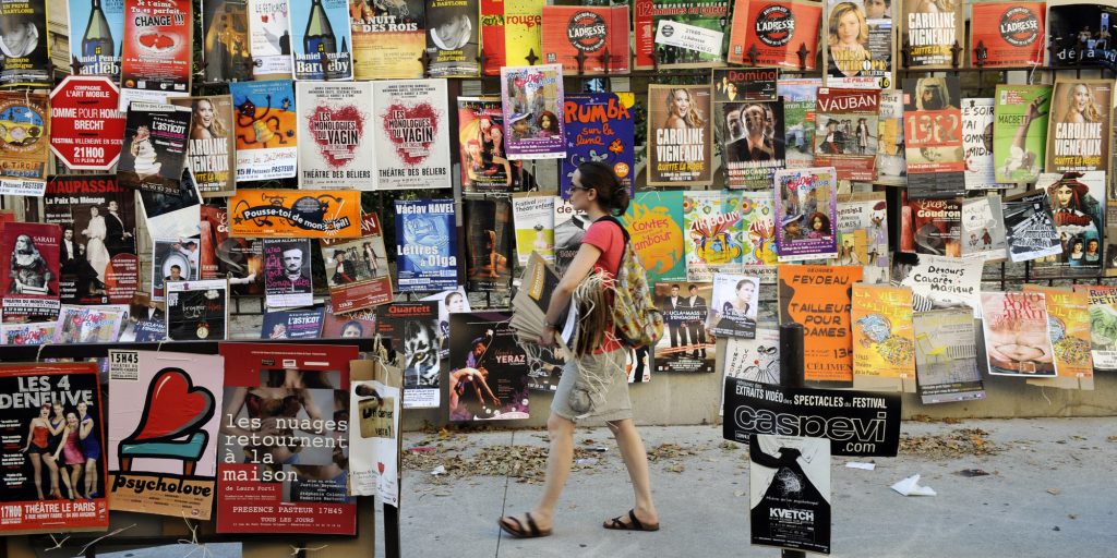 An actress walks with posters of her theater show which is to be performed during the Avignon "Off" Theater Festival, two days before the opening of the 64th official Avignon festival, on July 5, 2010 near the Palais des Papes in the French southeastern city of Avignon. The festival runs from July 7 to next July 21, 2010. AFP PHOTO ANNE-CHRISTINE POUJOULAT / AFP / ANNE-CHRISTINE POUJOULAT